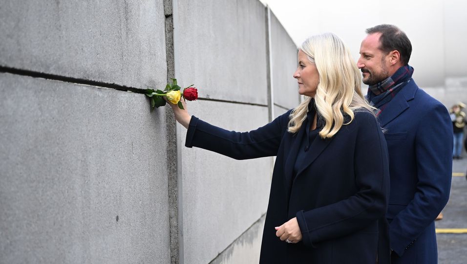 Der norwegische Kronprinz Haakon und die Kronprinzessin Mette-Marit stecken Rosen in die Mauer.