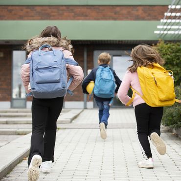 Kinder rennen in die Schule