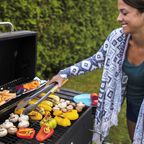 Slim young woman grilling vegetables