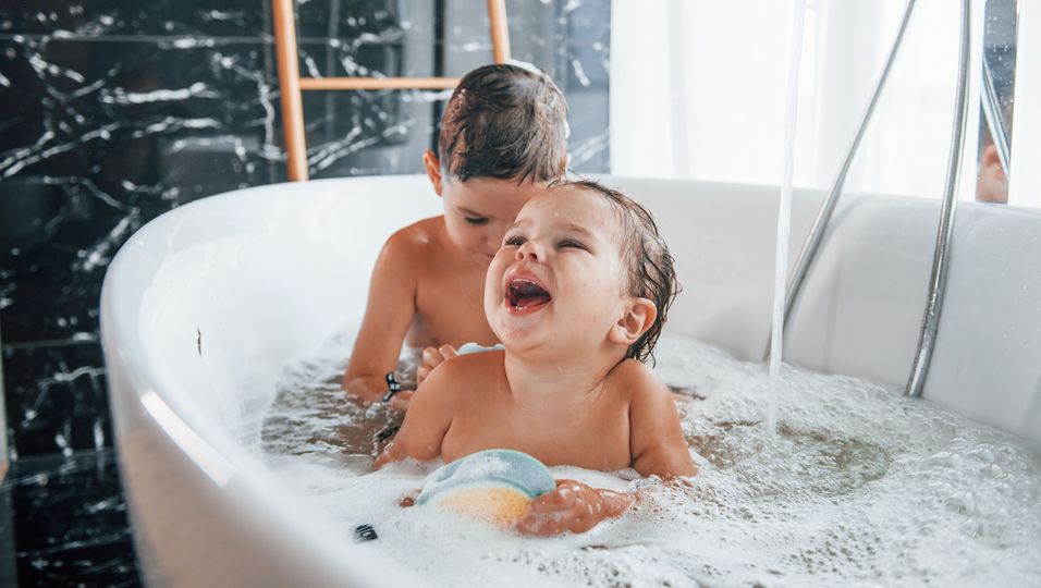 Zwei Kinder baden in der Badewanne.