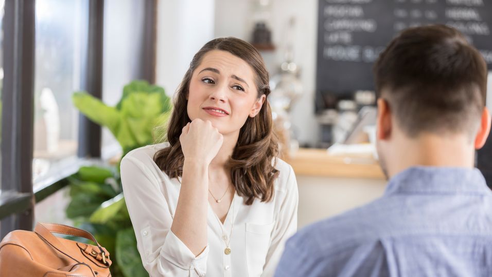 Frau schaut Mann skeptisch an bei einem Date im Café