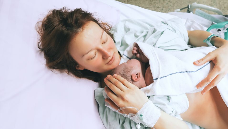 Mutter hält ihr Baby nach der Geburt im Krankenhaus im Arm