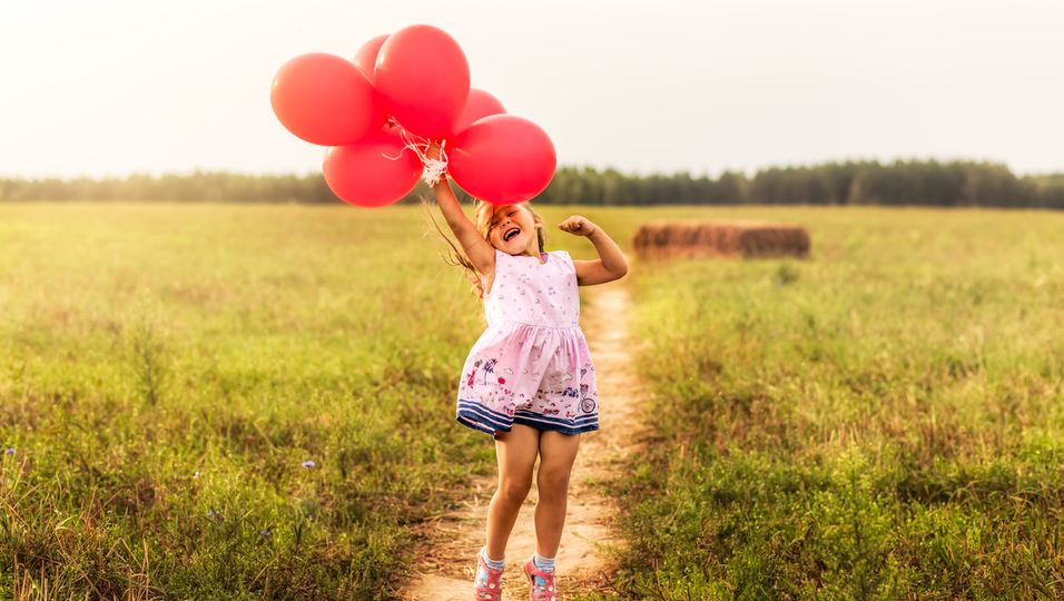 Kleines Mädchen lässt rote Luftballons steigen