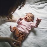 Frau legt schreiendes Baby ins Bett