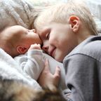 Kleiner Junge kuschelt mit seinem Babybruder