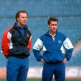 Bundestrainer Franz Beckenbauer steht neben Pierre Littbarski, der die Hände in den Hüften hat.
