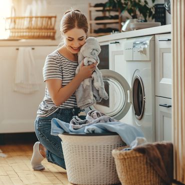Frau füllt Wäsche in Waschmaschine