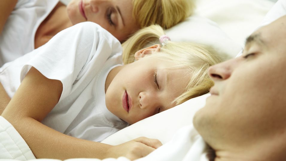 Kind schläft im Bett der Eltern