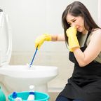Frau reinigt übel riechende Toilette