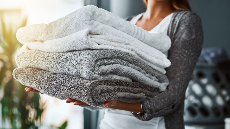 Frau hält einen Stapel mit gewaschenen Handtüchern im Arm