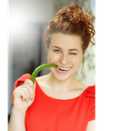 Junge Frau beißt auf eine grüne Chili-Schote