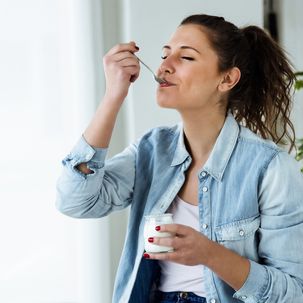 Frau isst genüsslich einen Joghurt