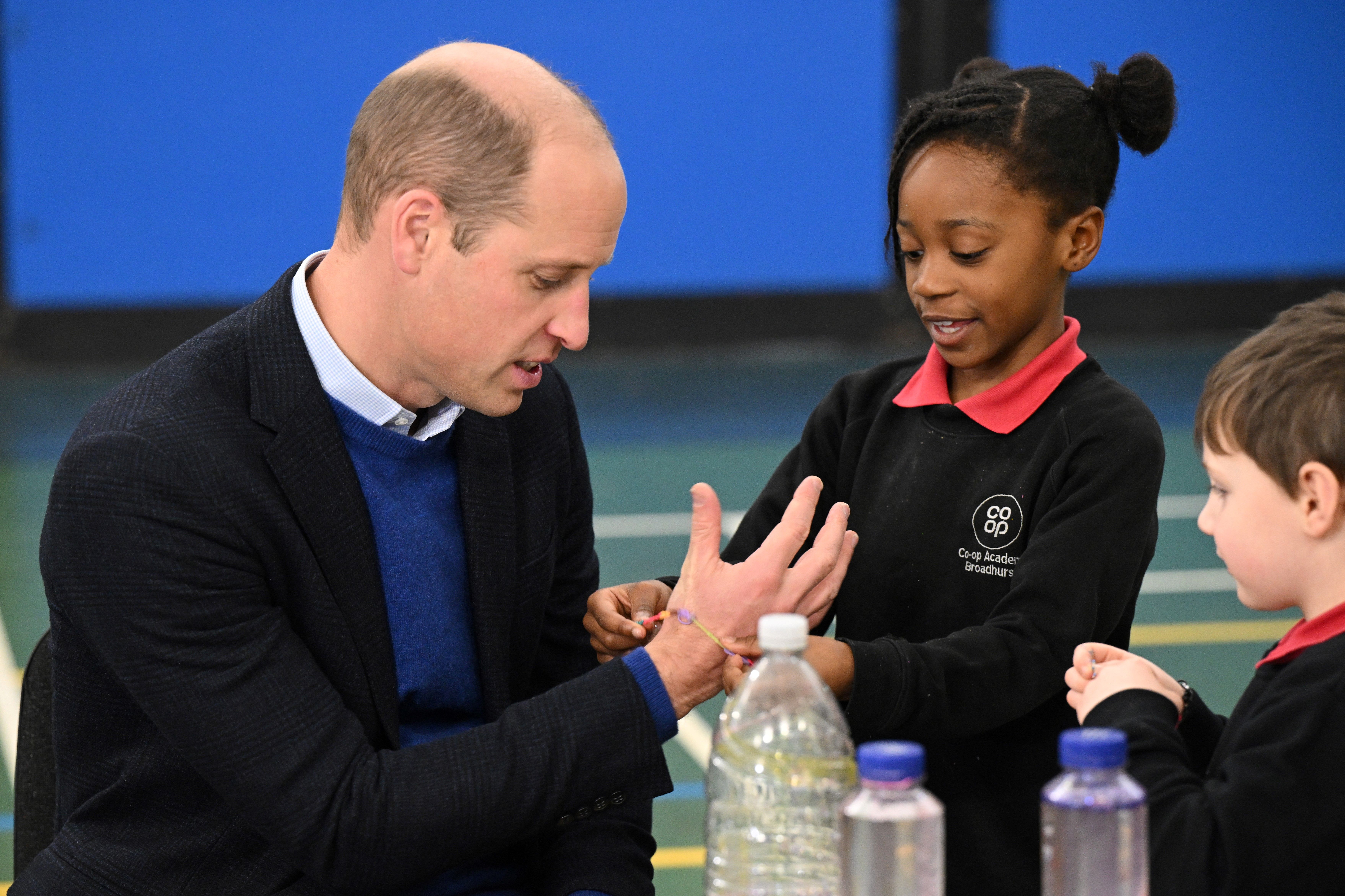 Prinz William erhält als Dank ein Freundschaftsarmband von einem Mädchen des Millennium Powerhouse.