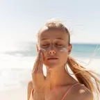 Frau mit Sonnencreme am Strand