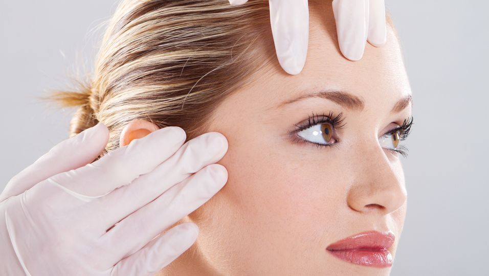 Frau bei der Gesichts-Hautuntersuchung beim Arzt