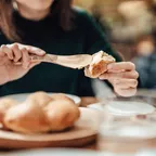 Frau beschmiert eine Scheibe Brot mit Butter