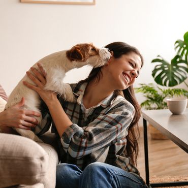 Frau hält Hund im Arm, der ihr Gesicht abschleckt