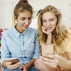 Zwei Frauen shoppen online über ihre Handys.