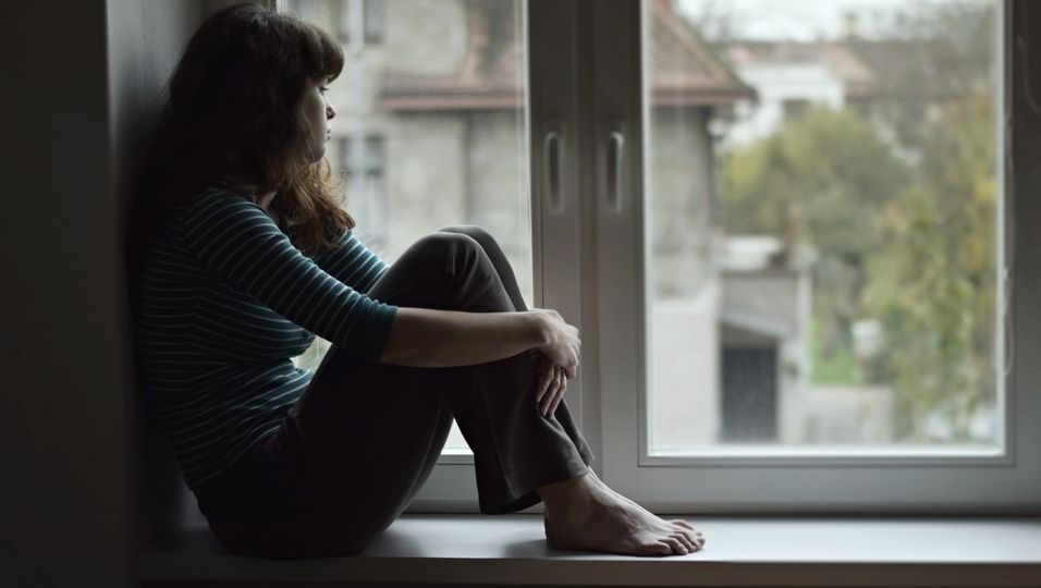 Traurige Frau auf Fensterbank