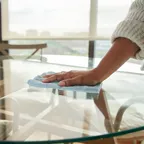 Frau wischt Glastisch ab