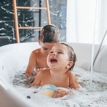 Zwei Kinder baden in der Badewanne.