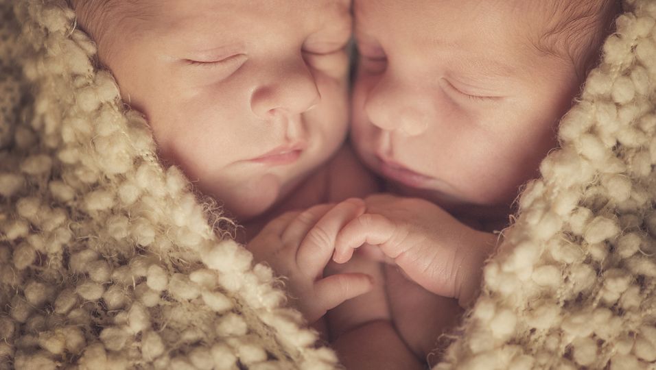 Neugeborene Zwillinge, die sich aneinander schmiegen
