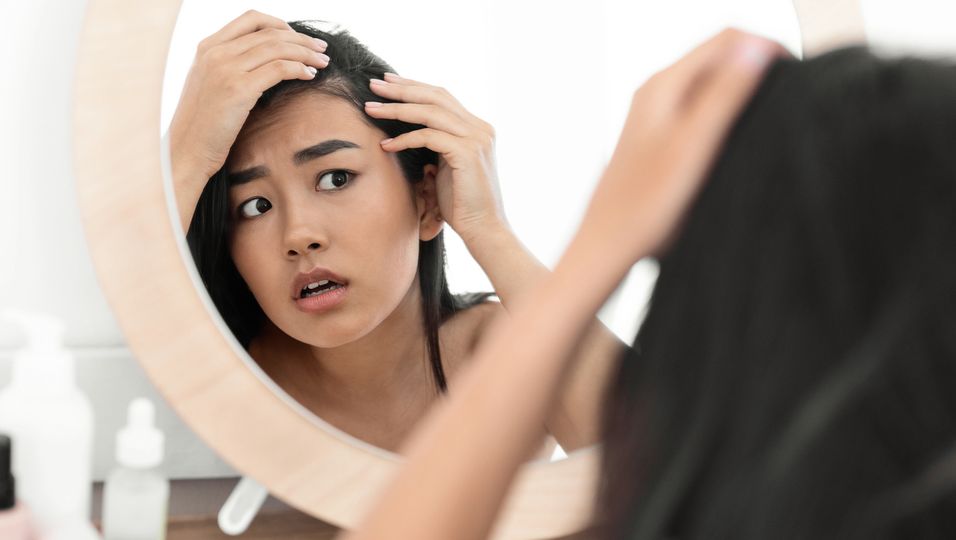 Frau kontrolliert Haare im Spiegel