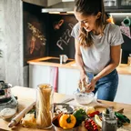 Frau, die an einer Kücheninsel steht und Zutaten vorbereitet