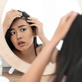 Frau kontrolliert Haare im Spiegel