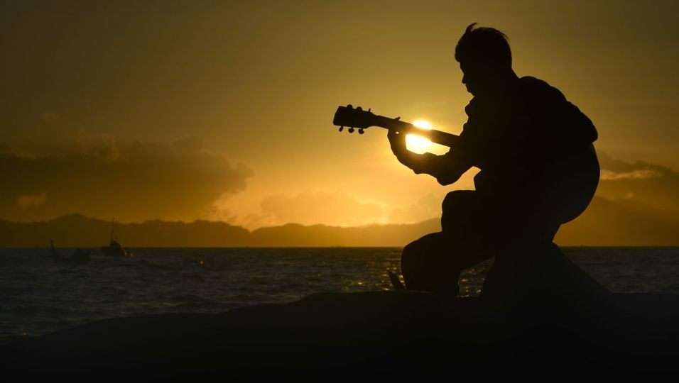 Junge spielt Gitarre am Meer