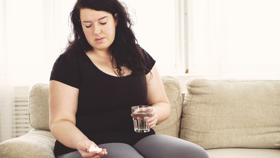 Übergewichtige Frau mit Pillen