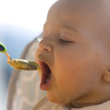 Kind wird mit Babylöffel gefüttert