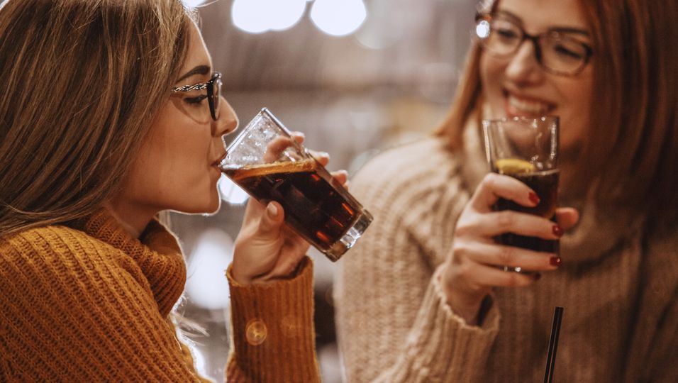Zwei Frauen trinken ein Glas Cola