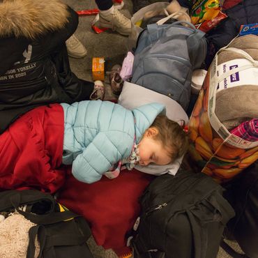 Ein ukrainisches Kind schläft am 9. März in eine Decke gehüllt auf dem Boden des Berliner Hauptbahnhofes