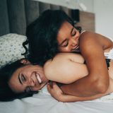 Zwei Frauen in Unterwäsche, die auf einem Bett kuscheln