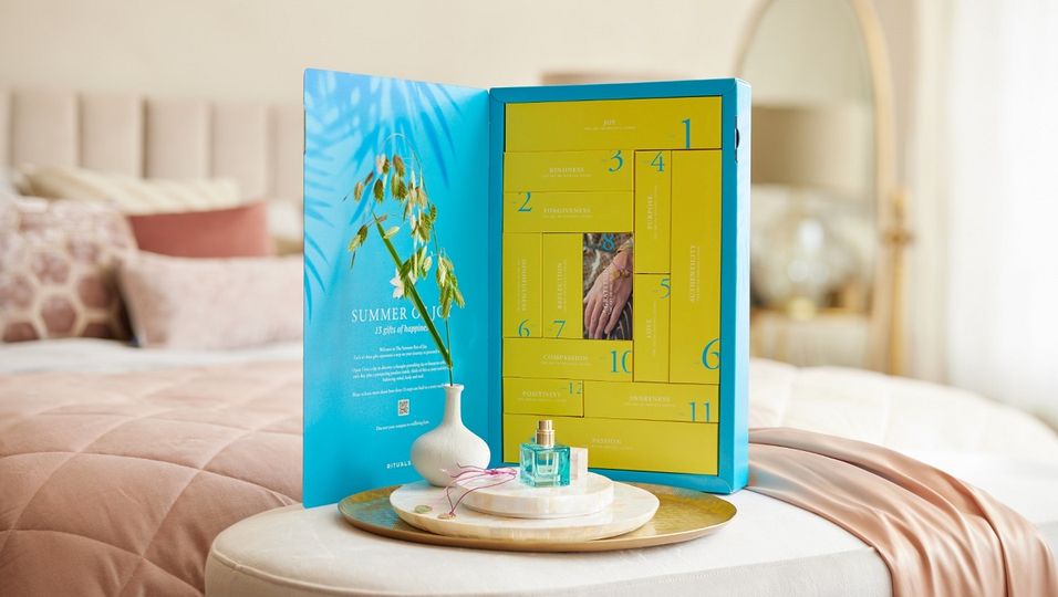 Das Bild zeigt die sommerliche Geschenkbox Summer of Joy. Die leuchtend blaue und gelbe Box mit den 13 Schachteln ist auf einem Tisch positioniert.