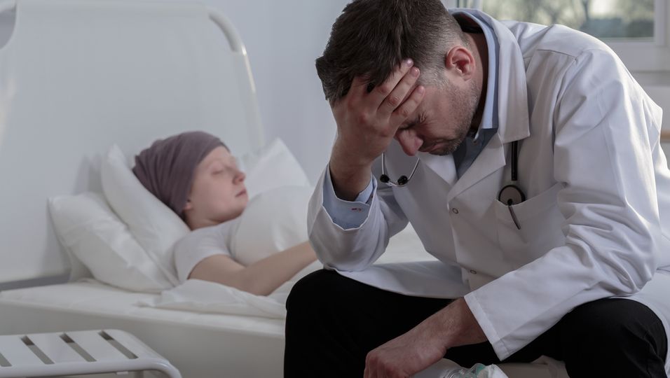 Arzt hilflos am Krankenbett einer Krebspatientin