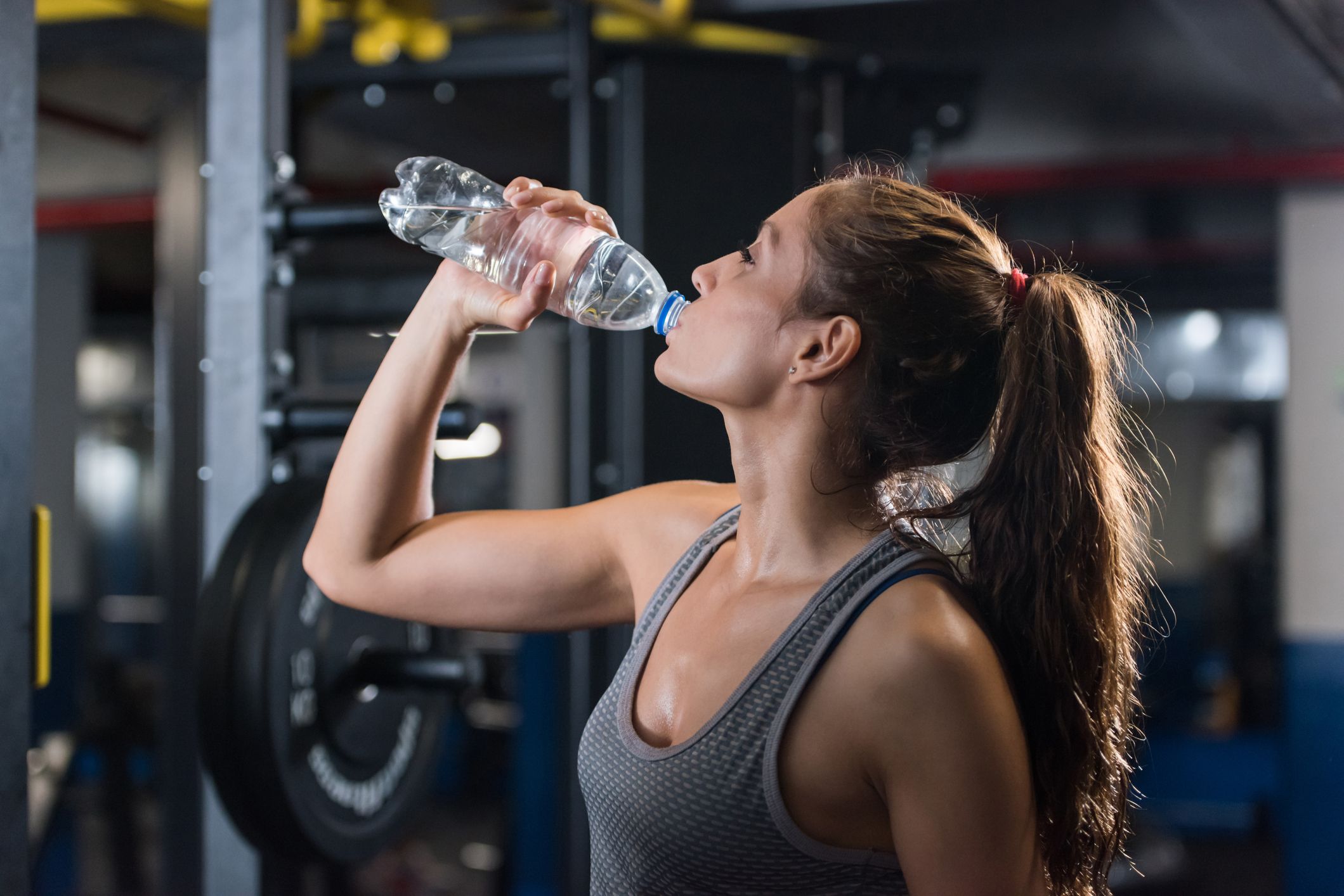 Frau trinkt Wasser im Fitnessstudio