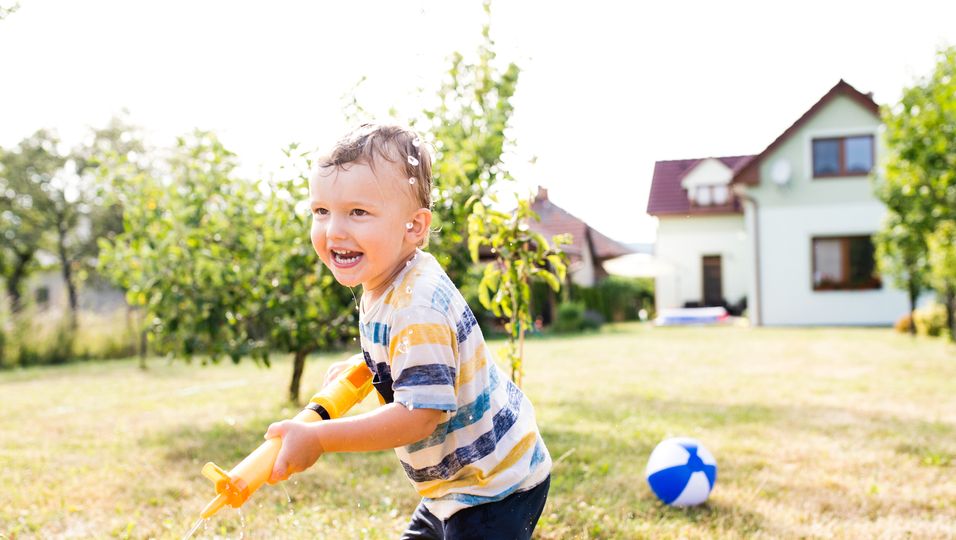 Junge mit Wasserpistole spielt im Garten