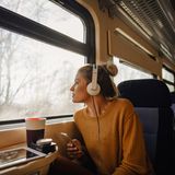 Frau, die in einem Zug sitzt und aus dem Fenster schaut