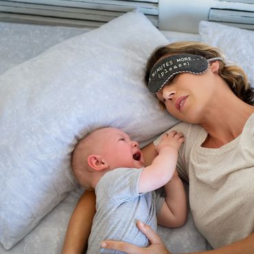 Weinendes Baby mit schlafender Mutter