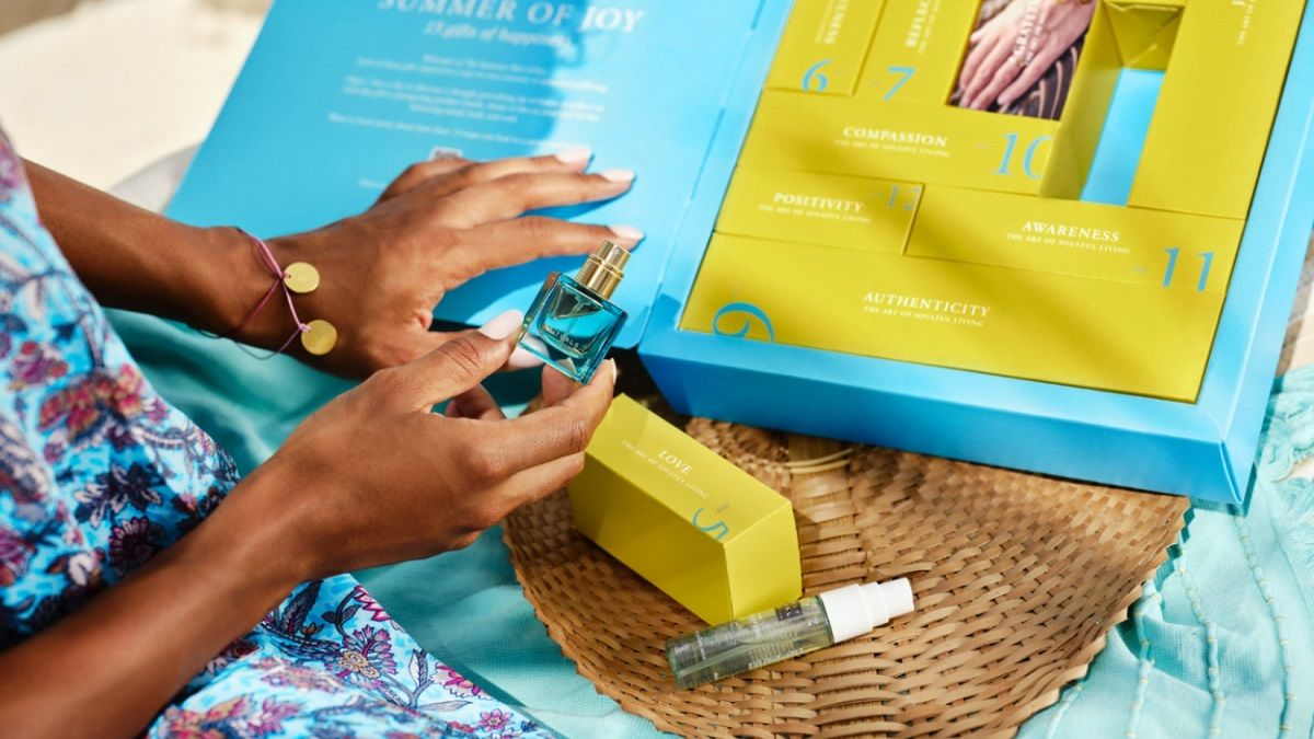 Eine Person öffnet eine Box des Summer of Joy Geschenksets. In der gelben Schachtel befindet sich eine Flasche Parfum.