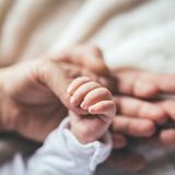 Eltern halten die Hand des Neugeborenen