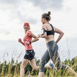 Zwei Frauen, die durch ein Feld joggen.