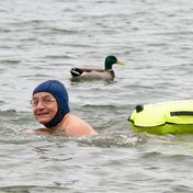 Comedian Wigald Boning schwimmt neben einer Ente in einem See.