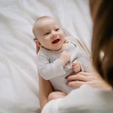 Ein Baby lacht seine Mutter an (Symbolbild). 