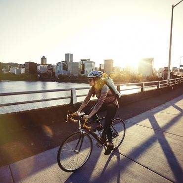 Frau fährt mit dem Fahrrad über eine Brücke in eienr Stadt