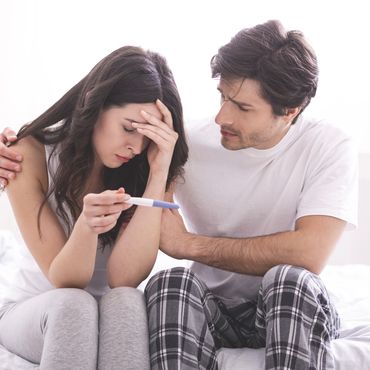 Symbolbild: Mann tröstet seine Frau mit negativem Schwangerschaftstest.