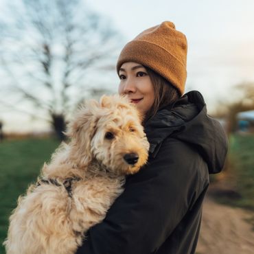 Frau hält Hund auf dem Arm und lächelt